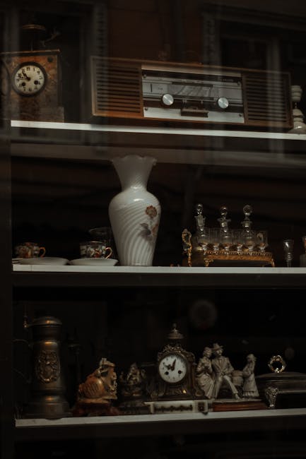 A collection of framed artwork and photographs leaning against each other on a black surface, likely inside a property or on a vehicle's loading area, with some frames made of wood and others with dec